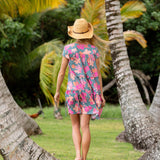 woman with brown hair wearing a teal v neck flowy dress with orange and pink floral print