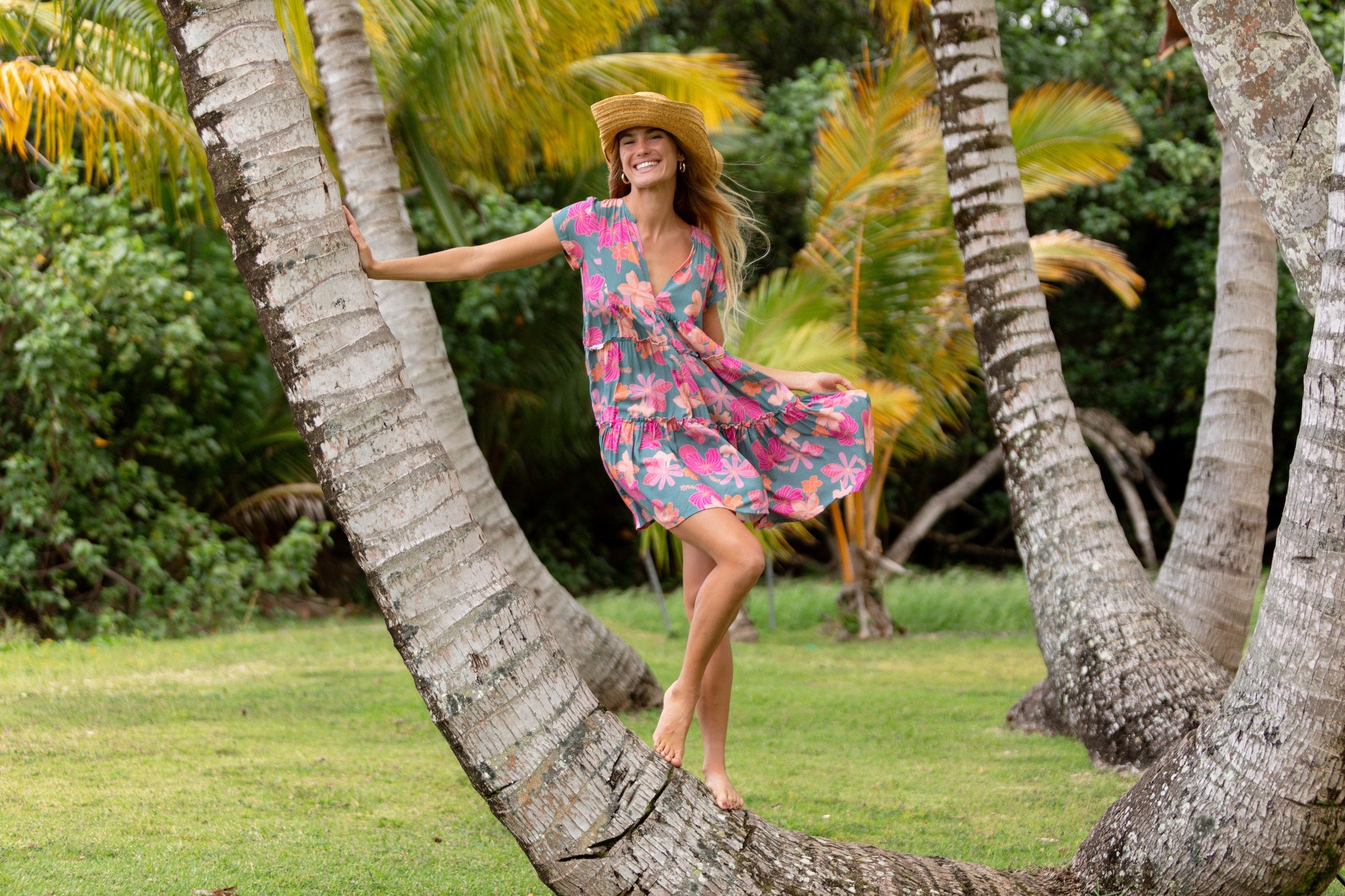 woman with brown hair wearing a teal v neck flowy dress with orange and pink floral print