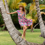 woman with brown hair wearing a teal v neck flowy dress with orange and pink floral print