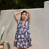 woman with black hair wearing a mini tiered dress in a navy color with pink hibiscus blossoms 
