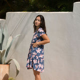 woman with black hair wearing a mini tiered dress in a navy color with pink hibiscus blossoms 