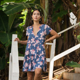 woman with black hair wearing a mini tiered dress in a navy color with pink hibiscus blossoms 