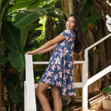 woman with black hair wearing a mini tiered dress in a navy color with pink hibiscus blossoms 