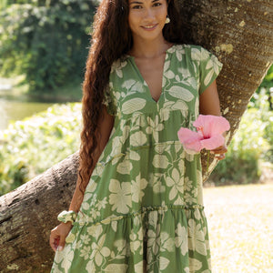 woman wearing green flowy tiered short dress with native Hawaiian plants