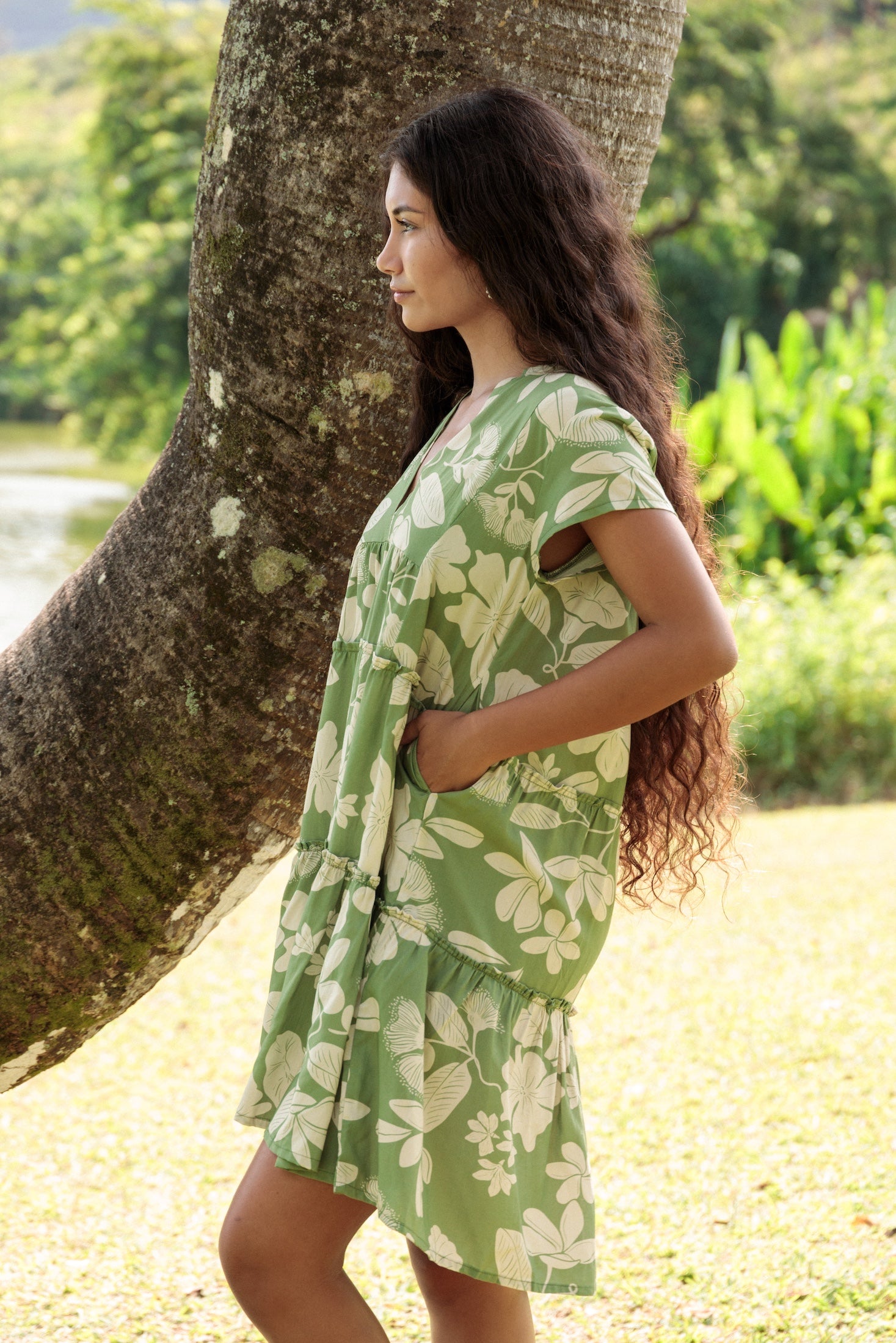 woman wearing green flowy tiered short dress with native Hawaiian plants