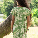 woman wearing green flowy tiered short dress with native Hawaiian plants