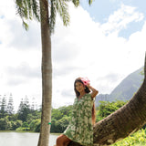 woman wearing green flowy tiered short dress with native Hawaiian plants