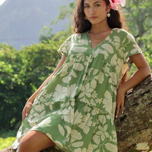 woman wearing green flowy tiered short dress with native Hawaiian plants