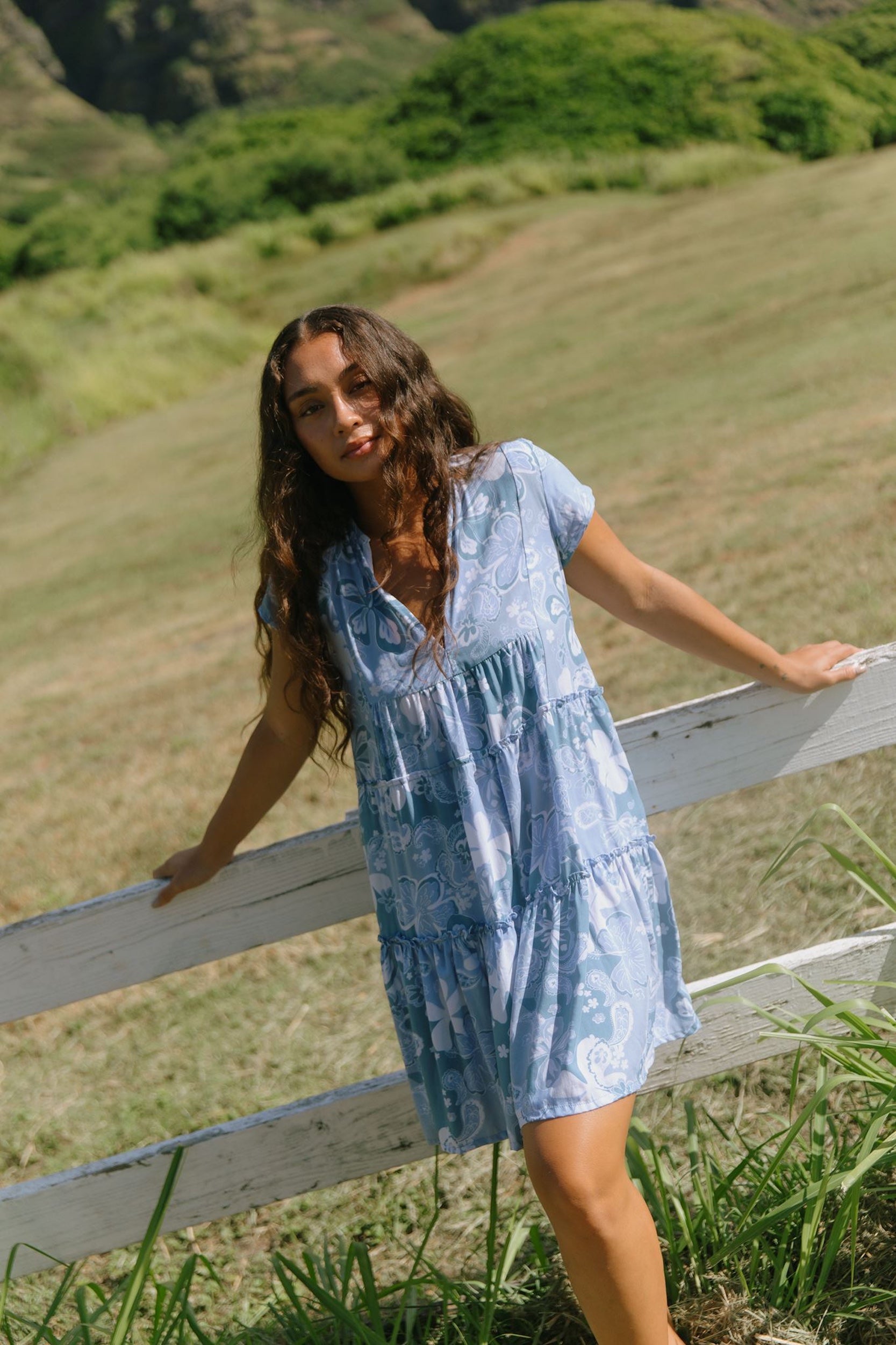 woman with brown hair wearing blue paisley printed short flowy dress with v neck