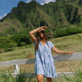 woman with brown hair wearing blue paisley printed short flowy dress with v neck