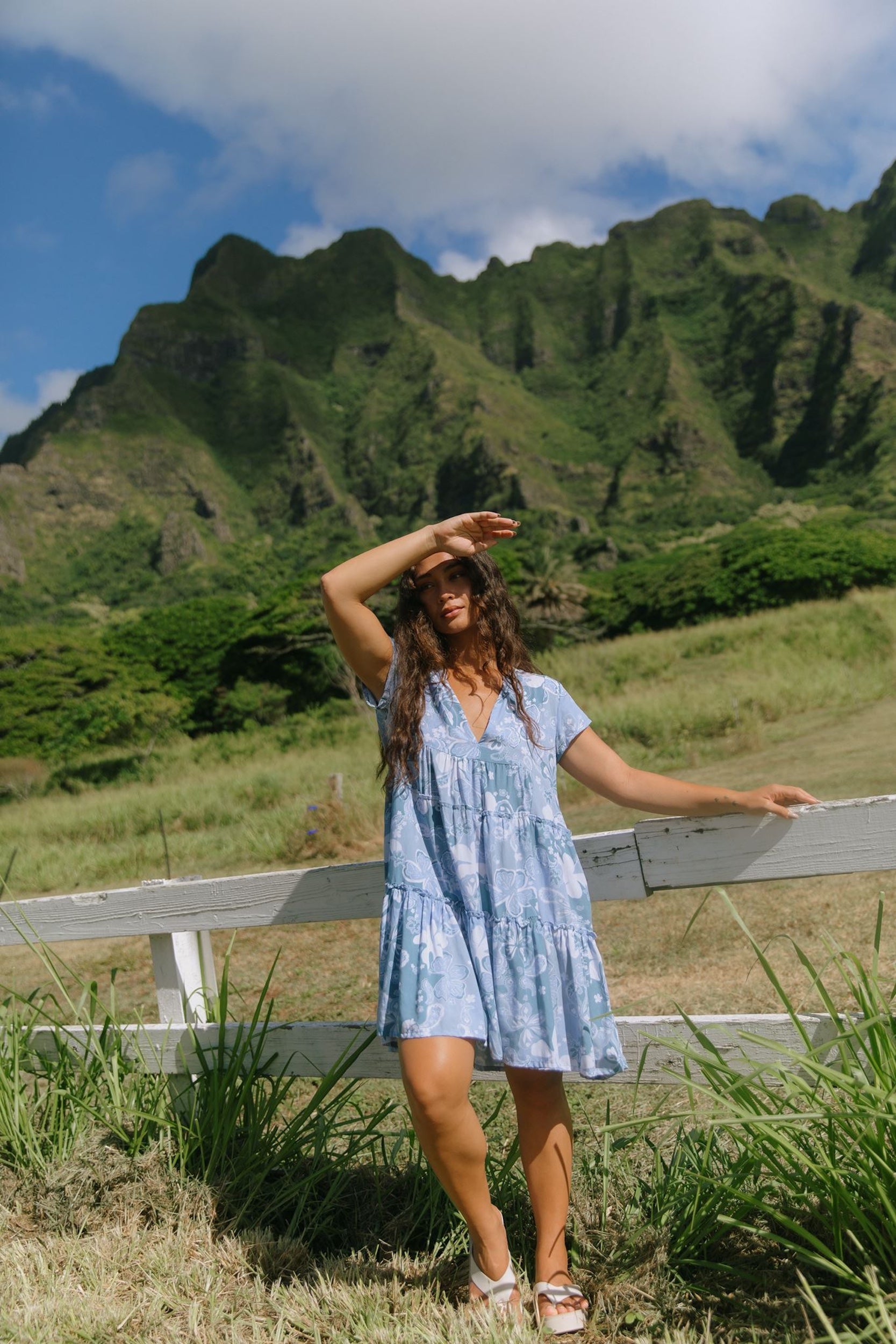 woman with brown hair wearing blue paisley printed short flowy dress with v neck