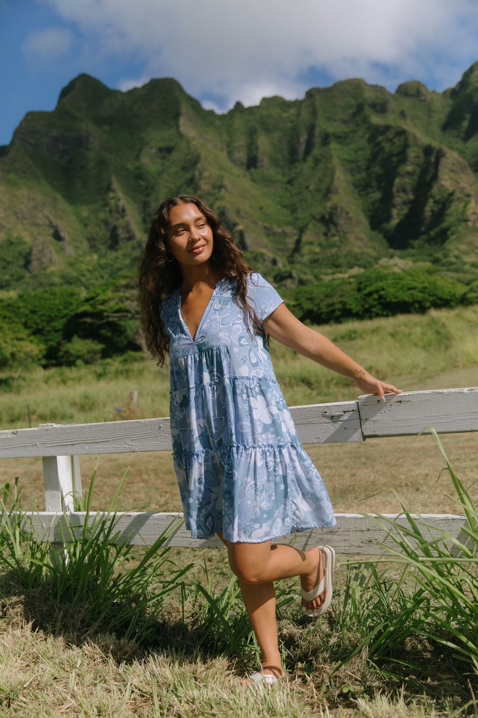 woman with brown hair wearing blue paisley printed short flowy dress with v neck