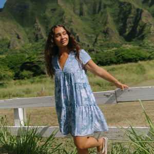 woman with brown hair wearing blue paisley printed short flowy dress with v neck