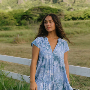 woman with brown hair wearing blue paisley printed short flowy dress with v neck