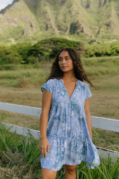 woman with brown hair wearing blue paisley printed short flowy dress with v neck