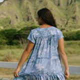 woman with brown hair wearing blue paisley printed short flowy dress with v neck