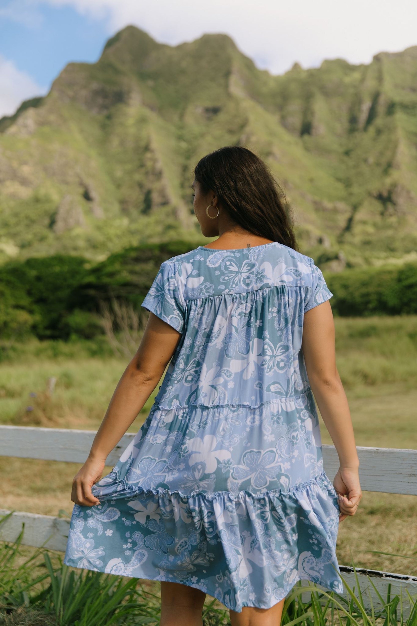 woman with brown hair wearing blue paisley printed short flowy dress with v neck