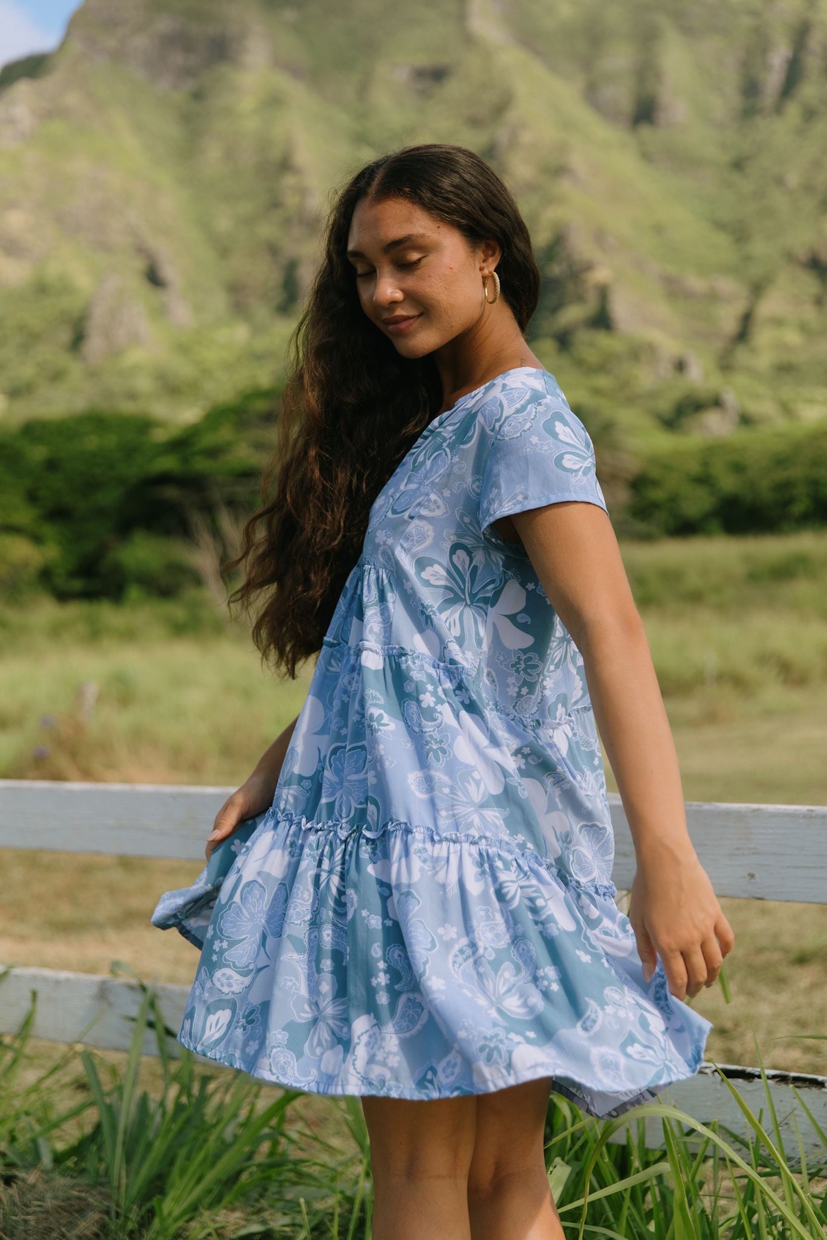 woman with brown hair wearing blue paisley printed short flowy dress with v neck