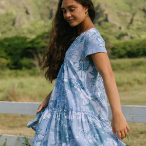 woman with brown hair wearing blue paisley printed short flowy dress with v neck