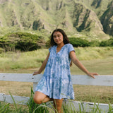 woman with brown hair wearing blue paisley printed short flowy dress with v neck