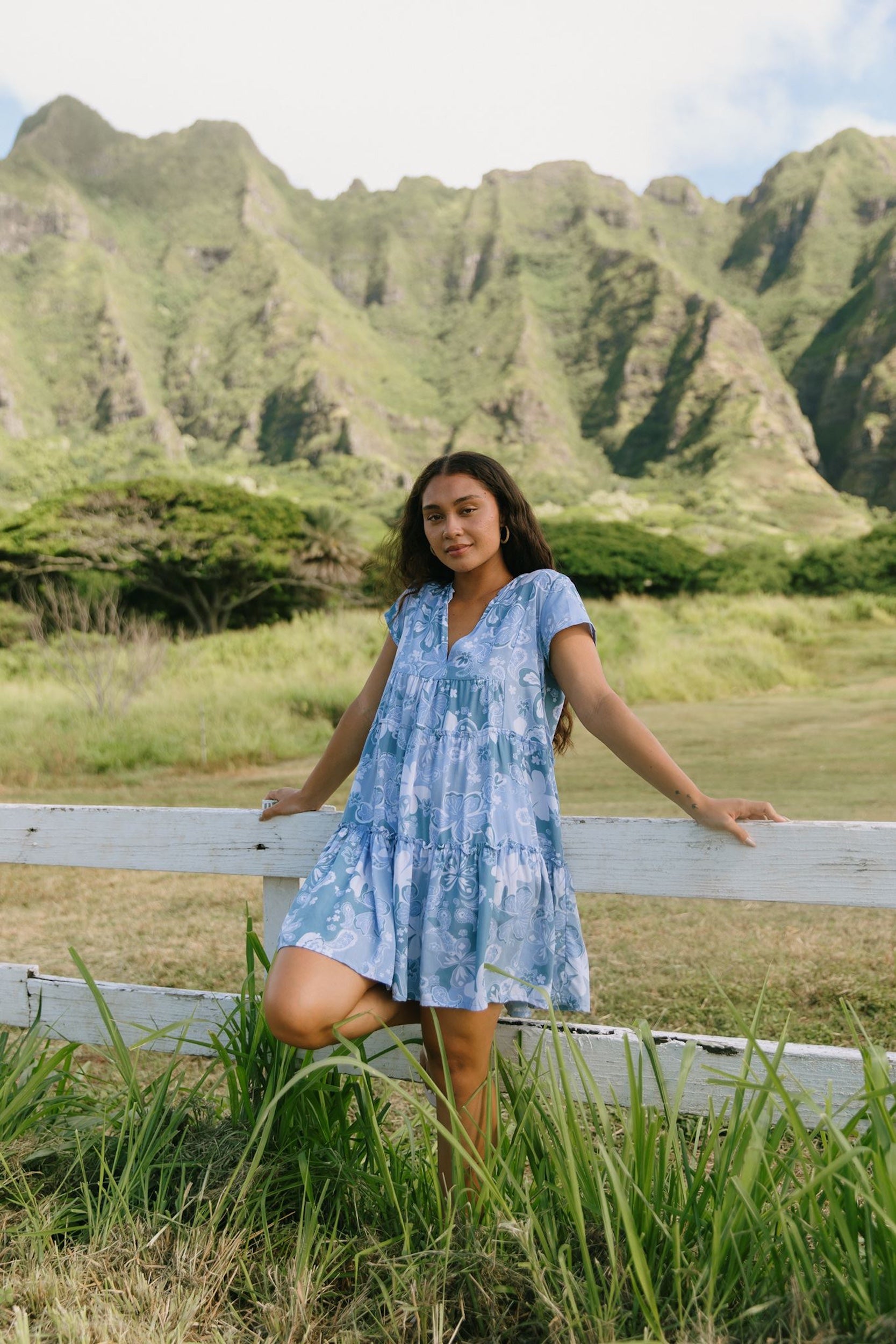 woman with brown hair wearing blue paisley printed short flowy dress with v neck