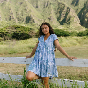 woman with brown hair wearing blue paisley printed short flowy dress with v neck