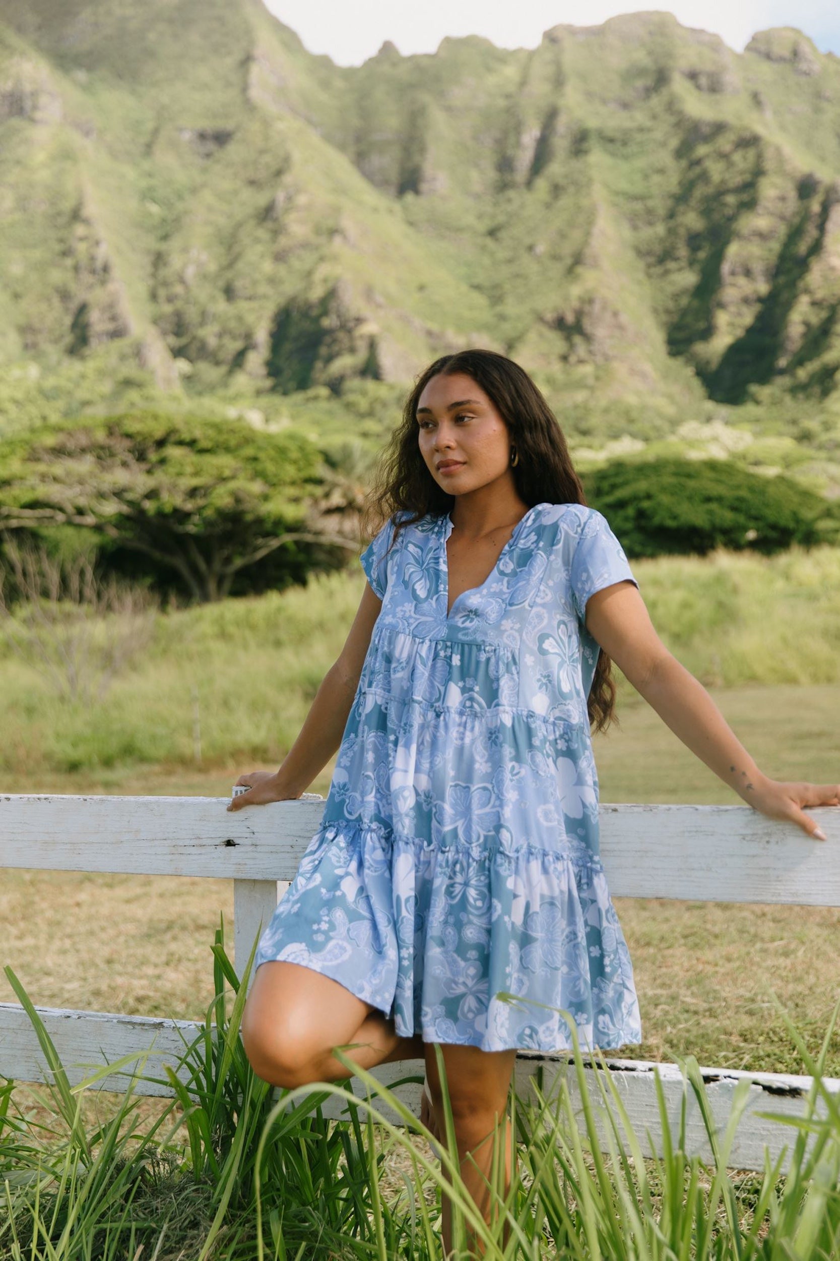 woman with brown hair wearing blue paisley printed short flowy dress with v neck