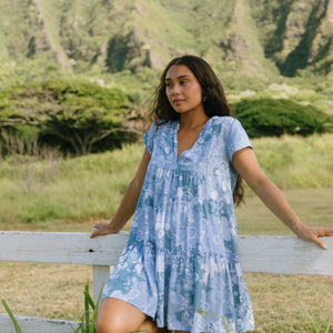 woman with brown hair wearing blue paisley printed short flowy dress with v neck