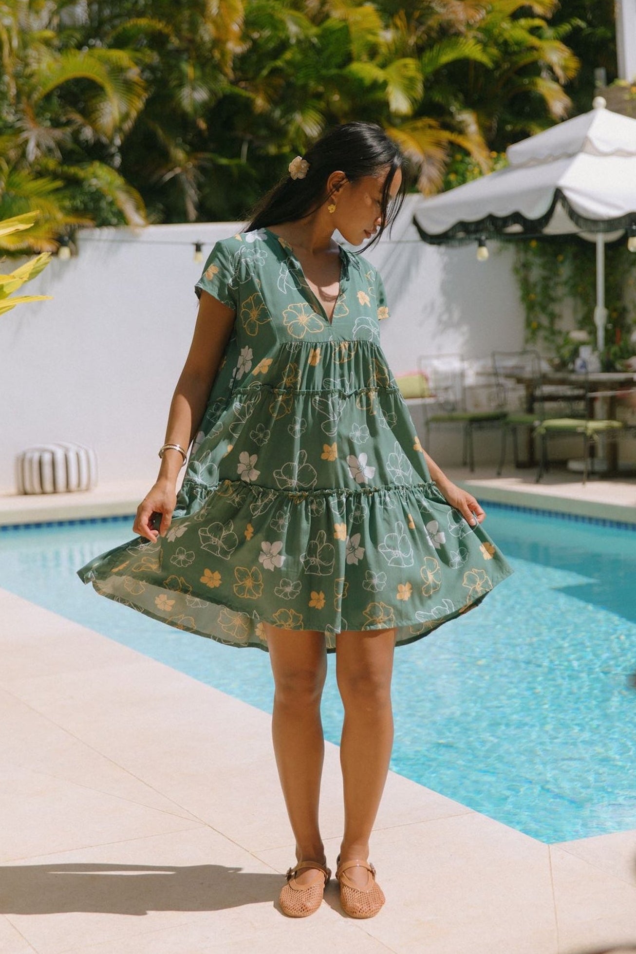 woman with brown hair wearing lush green v-neck tiered mini dress with puakenikeni print