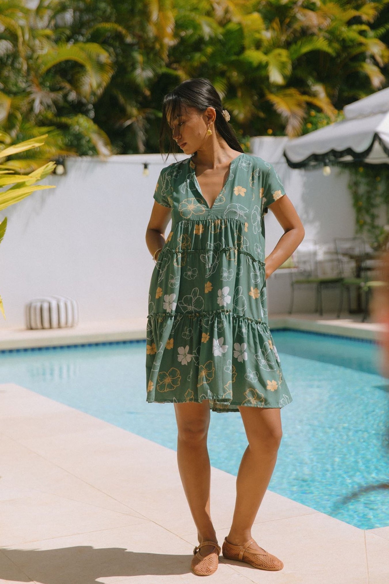 woman with brown hair wearing lush green v-neck tiered mini dress with puakenikeni print