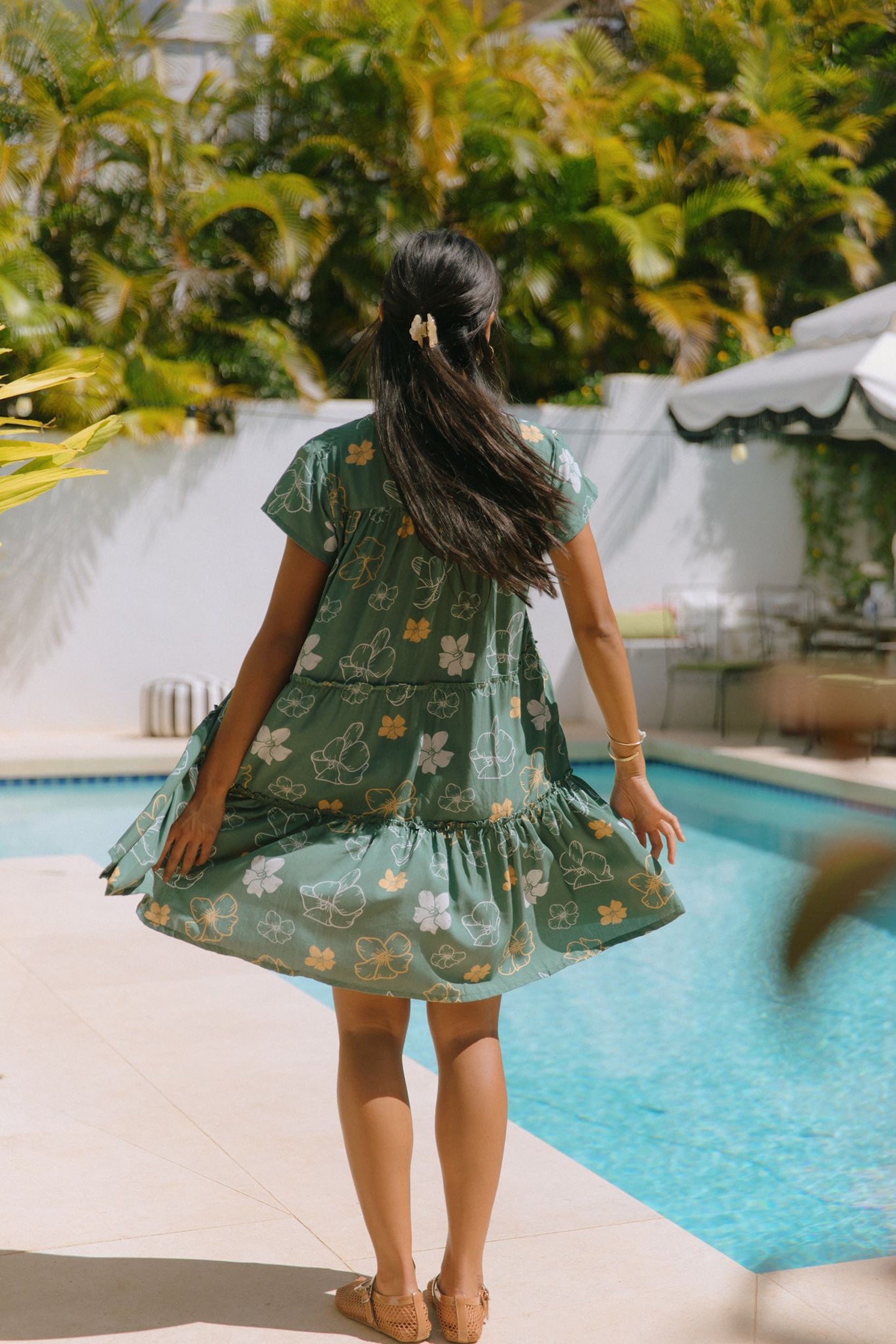 woman with brown hair wearing lush green v-neck tiered mini dress with puakenikeni print