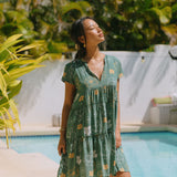 woman with brown hair wearing lush green v-neck tiered mini dress with puakenikeni print