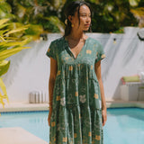 woman with brown hair wearing lush green v-neck tiered mini dress with puakenikeni print