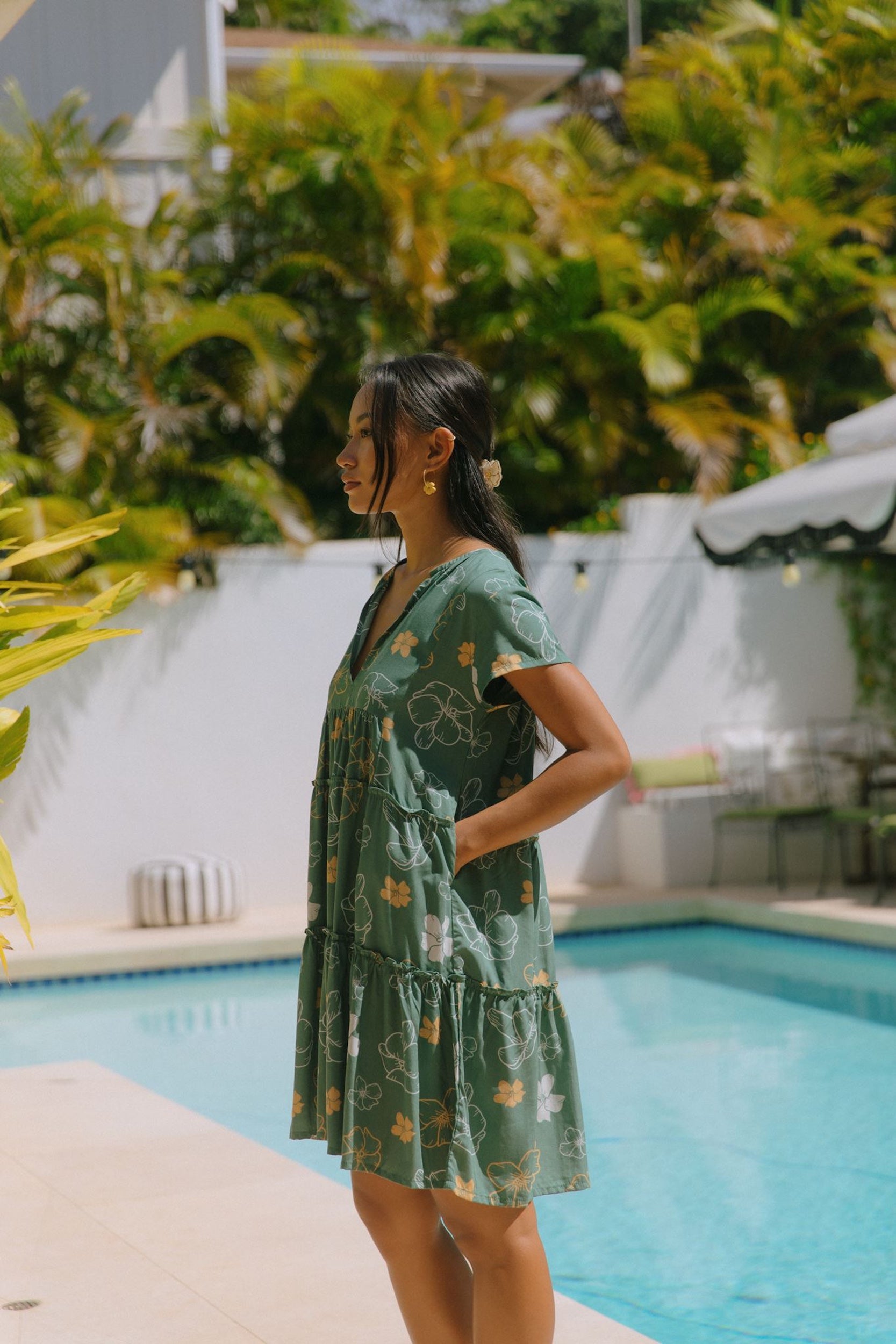 woman with brown hair wearing lush green v-neck tiered mini dress with puakenikeni print