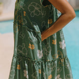 woman with brown hair wearing lush green v-neck tiered mini dress with puakenikeni print