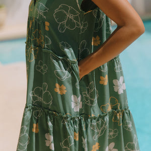 woman with brown hair wearing lush green v-neck tiered mini dress with puakenikeni print