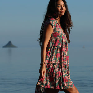 woman with brown hair wearing a baby doll dress with shell and pua print in a teal color