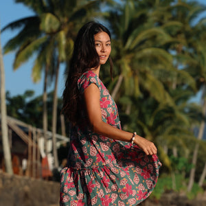 woman with brown hair wearing a baby doll dress with shell and pua print in a teal color
