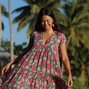 woman with brown hair wearing a baby doll dress with shell and pua print in a teal color
