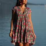 woman with brown hair wearing a baby doll dress with shell and pua print in a teal color