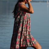 woman with brown hair wearing a baby doll dress with shell and pua print in a teal color