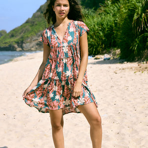 woman with brown hair wearing a deep v cut flowy dress with red ginger and tiare print 