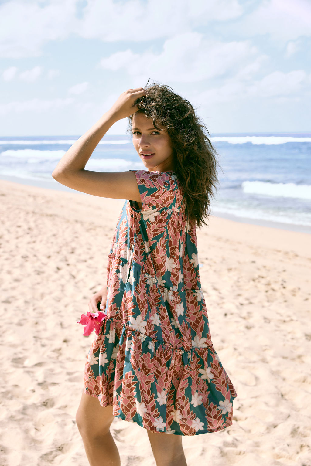 woman with brown hair wearing a deep v cut flowy dress with red ginger and tiare print 