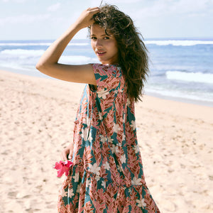 woman with brown hair wearing a deep v cut flowy dress with red ginger and tiare print 