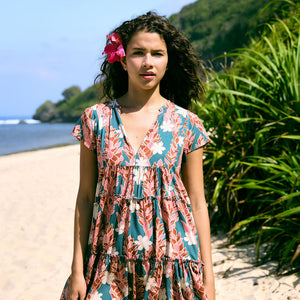 woman with brown hair wearing a deep v cut flowy dress with red ginger and tiare print 