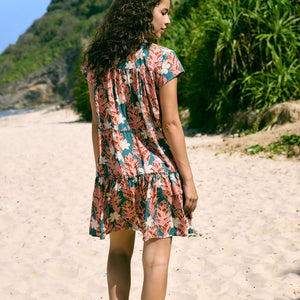 woman with brown hair wearing a deep v cut flowy dress with red ginger and tiare print 