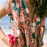 woman with brown hair wearing a deep v cut flowy dress with red ginger and tiare print 