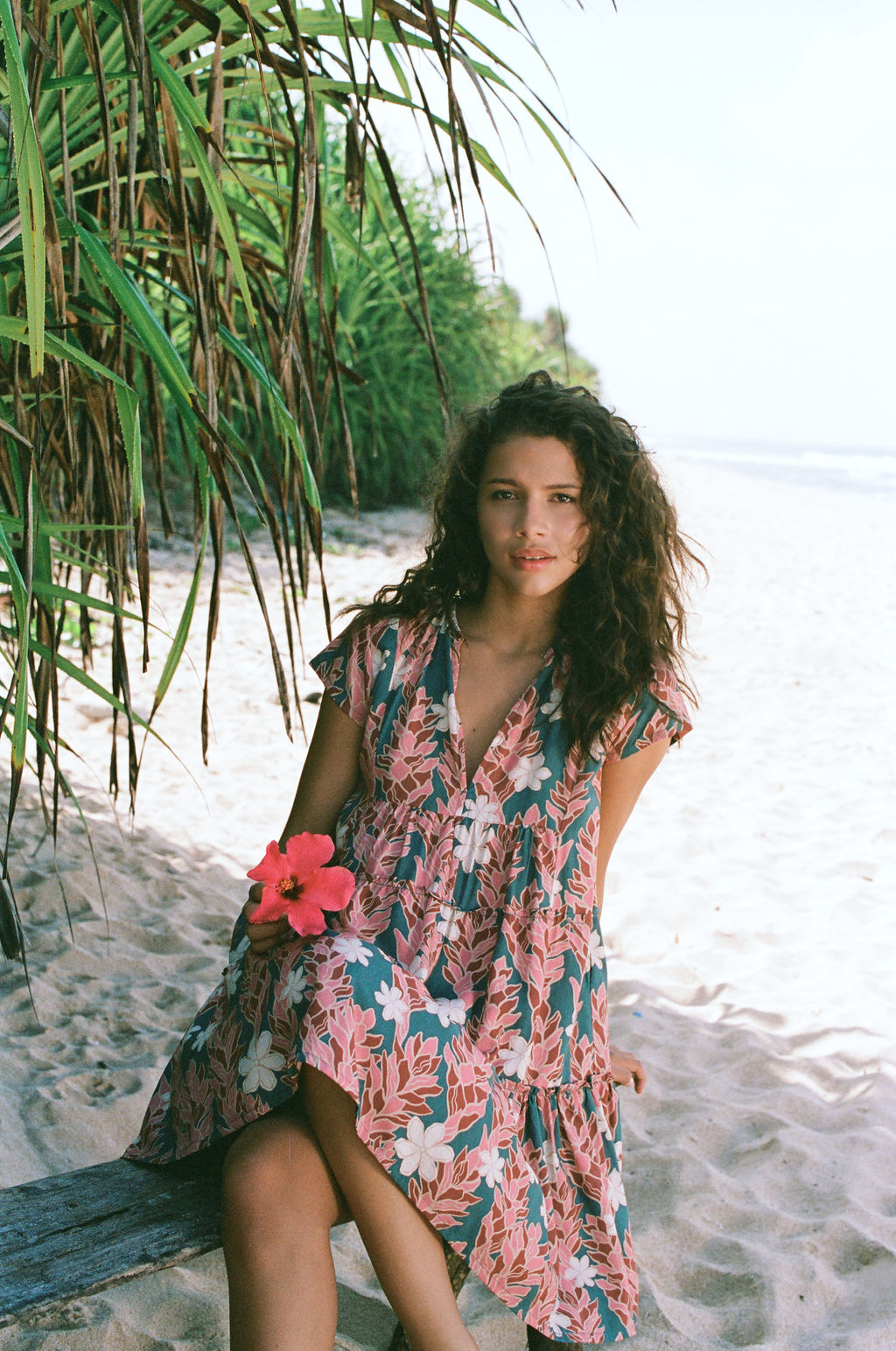 woman with brown hair wearing a deep v cut flowy dress with red ginger and tiare print 