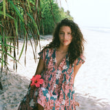 woman with brown hair wearing a deep v cut flowy dress with red ginger and tiare print 