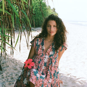 woman with brown hair wearing a deep v cut flowy dress with red ginger and tiare print 